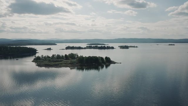 Aerial view; drone flying forward over flooded terrain with uninhabited island and wild flora and founa; untouched nature national in park in Ural; sunset evening time; boat trip between curved coasts