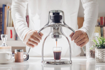 Man making espresso shot with classic espresso machine at home in the morning.