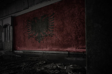 painted flag of albania on the dirty old wall in an abandoned ruined house.