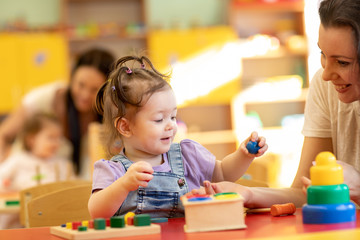 Babies with teachers playing with developmental toys in nursery - 271366477