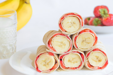 Vegetarian strawberry banana rolled pancakes in shape of pyramidon white background