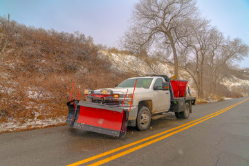 Vehicle travelling on a road along a mountain with snowy slope on a cloudy day