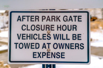 Obraz premium Close up of a sign at a park blanketed with snow during winter