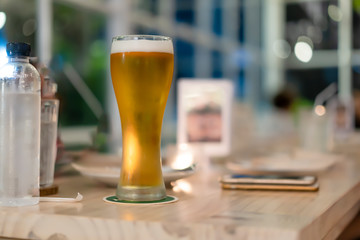 beer in a tall glass that is placed on the table.