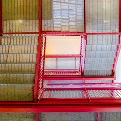 Stairs with grated treads and bright red handrails viewed from below