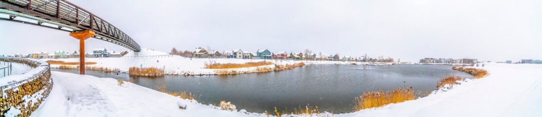 Fototapeta premium Silvery lake amid a scenic landscape blanketed with fresh snow in winter
