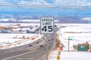 Close up of a Speed Limit sign at a highway surrounded with snow in winter