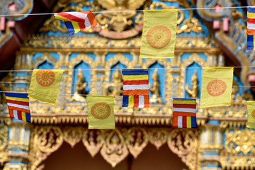 Small hanging Buddhist flags with blur Buddhist temple in background, Thailand 