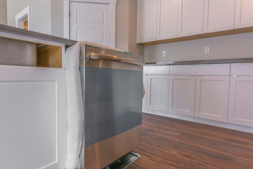 Fototapeta premium Close up of a dishwasher on a kitchen island against brown wooden floor