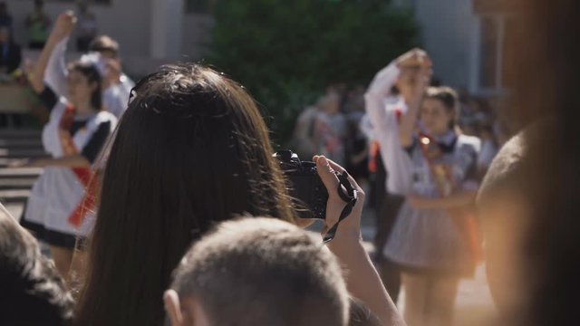 A woman photographs graduates in school