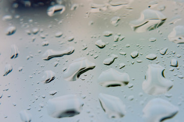 Large raindrops on clear glass on a rainy cloudy day