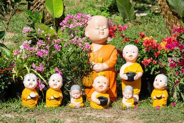 Red clay doll, little happy smiling monk and monkey, decoration in temple garden. Peaceful idea.