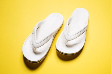 Flip flops on a yellow isolated background. White female flip flops.