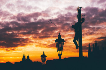Prague Castle at magic sunset. Statue of crucifixion on Charles bridge.