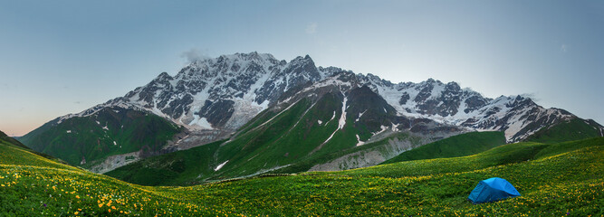 Panorama Svaneti mountains in Georgia. Landscape of Caucasus mountain range. Scenic mountains with tent in tourist camp