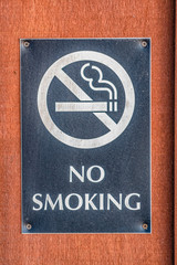 Obraz premium Close up of a No Smoking sign screwed to a reddish brown wood surface