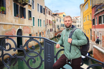 Fototapeta na wymiar Tourist man in Venice, Italy. Portrait of handsome young guy with backpack against venetian water canal