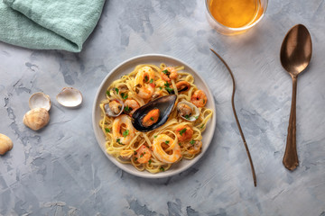 Seafood pasta. Tagliolini with mussels, shrimps, clams and squid rings, shot from above with a glass of white wine