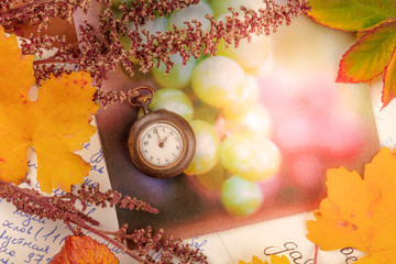 Nostalgic background with a place for text. A vintage watch with autumn leaves and old postcards, shot from the top