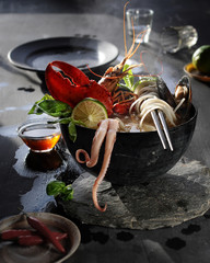 food photography of vietnamese asian pho soup with seafood, soy sauce and herbs in a dark bowl side...