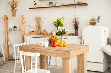Concept breakfast made from fruits and coffee or tea. Oranges, bananas, cups, peaches on a textural large wooden table against a background of rustic or Scandinavian cuisine