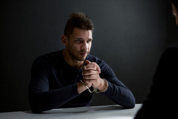 Suspect or criminal man with handcuffs in interrogation room