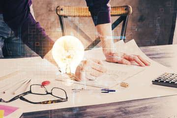 View of Bulb lamp idea concept icon on a futuristic interface with writing man's hand background. Double exposure.