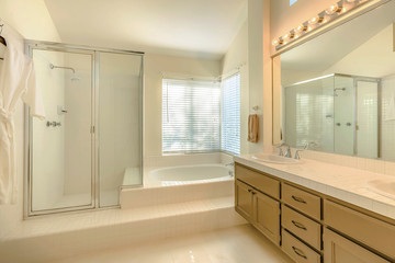 Bathtub and double vanity unit inside the well lighted bathroom of a home