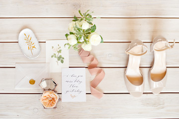 Elegant wedding bouquet with a ribbon, wedding invitation, rings and bridal shoes on tissue