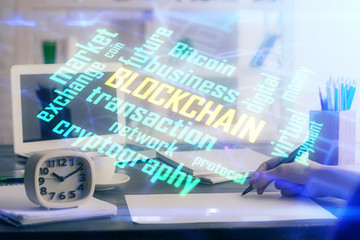 Cryptocurrency hologram over hands taking notes background. Concept of blockchain. Multi exposure