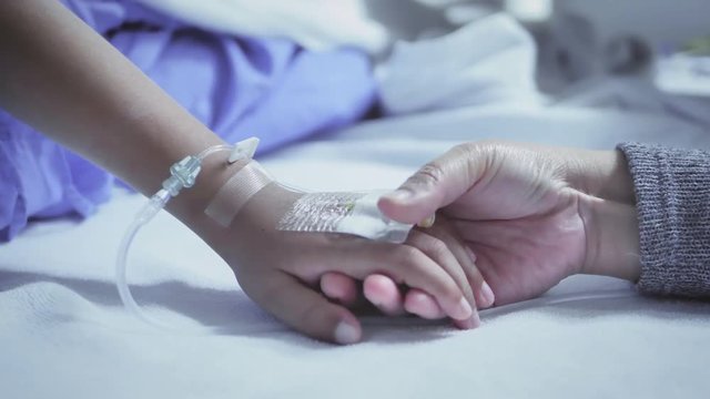 Mother holding hand of his son sick bed in the hospital. Touch the hand Slow motion. care encouragement