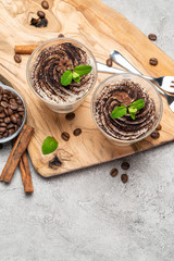 Classic tiramisu dessert in a glass on dark concrete background