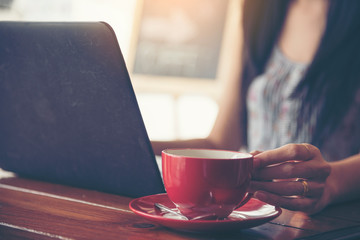 Woman with hot coffee cup. Young woman working on coffee shop holding cup of coffee