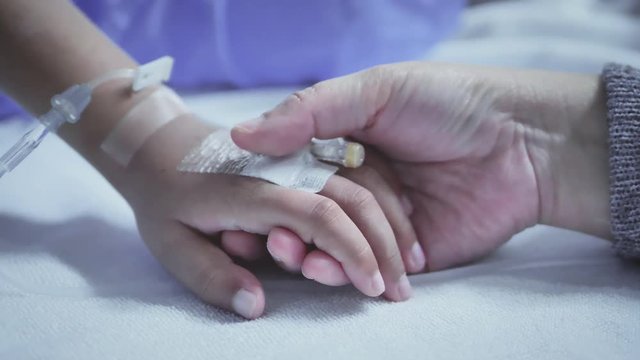 Mother holding hand of his son sick bed in the hospital. Touch the hand Slow motion. care encouragement