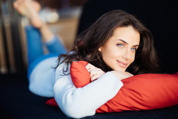 Young woman lying on couch cushion with eyes closed, relaxing on cozy sofa pillow. Relaxed girl taking nap at home hands behind head, breathing fresh air, no stress, enjoying day off in living room