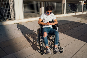 Obraz premium Portrait of cute boy sitting on wheelchair outdoor