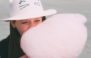 Adorable little preschool girl eating pink candy floss outdoors. Summer vacation concept