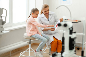 Interested smart child asking supportive beautiful doctor