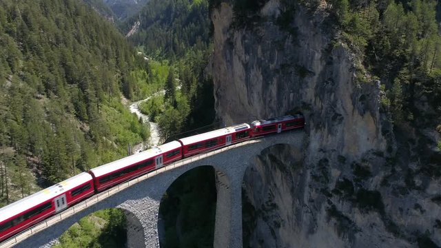Landwasser viaduct, red train on the railway. Unesco World Heritage. Aerial view 4k