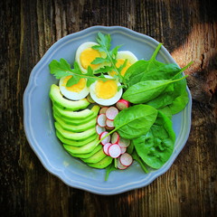Breakfast salad with radishes, boiled egg and mix lettuce leaves,spinach. Food background. Top view
