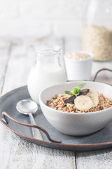 Healthy breakfast bowl. Granola with chocolate and banana on white wooden table. The concept of healthy nutrition and diet.