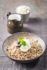 Healthy breakfast bowl. Granola with chocolate and banana on white wooden table. The concept of healthy nutrition and diet.