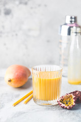 Tropical Mango smoothie in a glass and fresh mango on a light background. Mango shake. Tropical fruit concept.