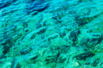 Transparent turquoise sea with sun glare. Background close-up. Space for text.