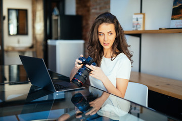 Freelance photographer woman with camera at home office editing photos on laptop