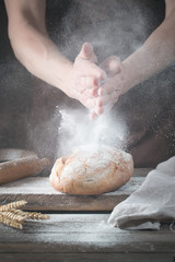 Baker cooking bread. Man slaps flour over the dough. Man's hands Making bread