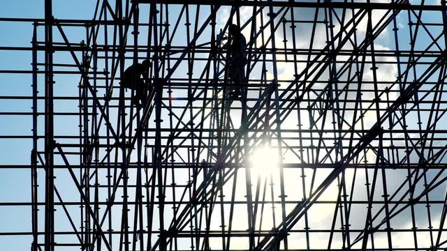 Workers at sunset builders assemble design. Silhouettes of men engineer worker at construction site. Concept building silhouette. Blue sky color. Construction equipment. Contrast background.