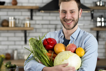 Obraz premium Handsome man carrying raw vegetables in kitchen