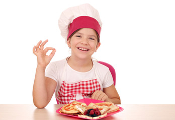 Happy little girl cook with sweet crepes and ok hand sign
