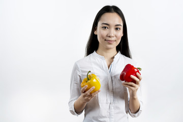 Front view of woman holding red and yellow bell pepper standing in front of isolated background